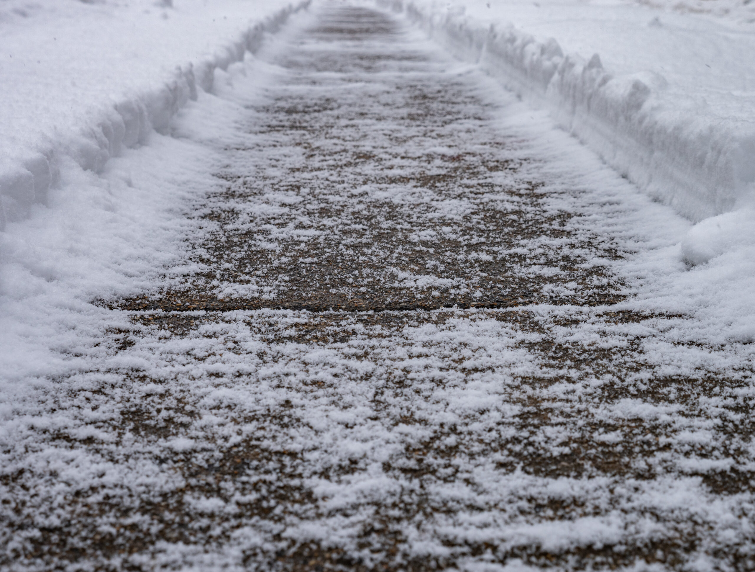 A sidewalk covered in powdery snow