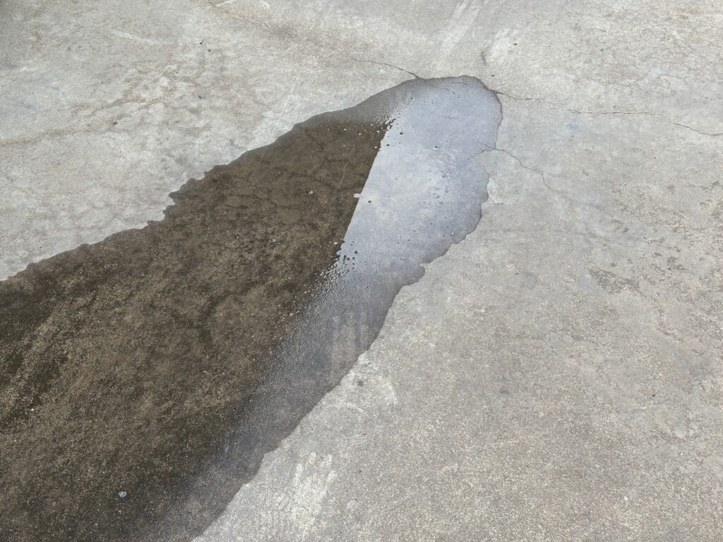 A puddle of water on a concrete driveway
