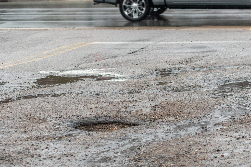 A parking lot with smaller sink holes and puddles